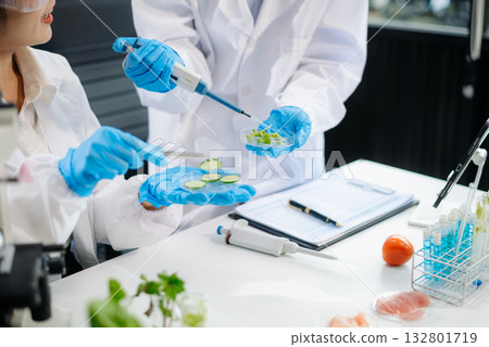 Two Asian scientists in a lab conducting food research using a microscope and lab equipment, showcasing innovation in food science 132801719