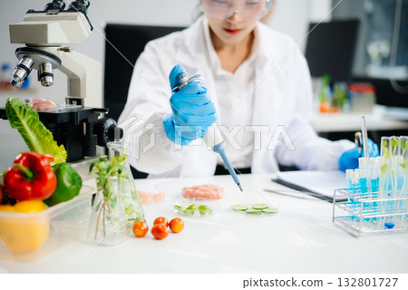 Two Asian scientists in a lab conducting food research using a microscope and lab equipment, showcasing innovation in food science 132801727