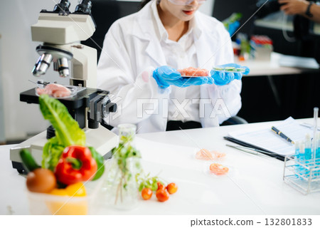 Two Asian scientists in a lab conducting food research using a microscope and lab equipment, showcasing innovation in food science Two Asian scientists in a lab conducting food research using a microscope and lab equipment, showcasing innovation in food science 132801833