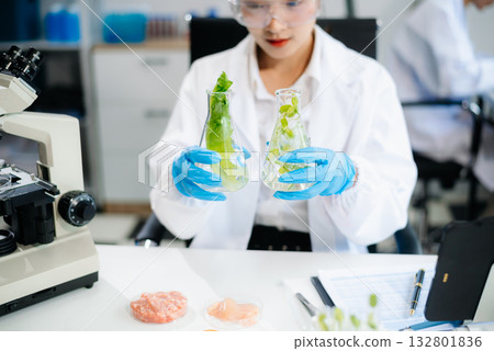 Two Asian scientists in a lab conducting food research using a microscope and lab equipment, showcasing innovation in food science 132801836