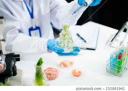 Two Asian scientists in a lab conducting food research using a microscope and lab equipment, showcasing innovation in food science 132801941
