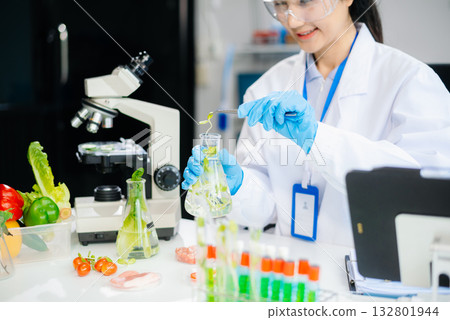 Two Asian scientists in a lab conducting food research using a microscope and lab equipment, showcasing innovation in food science Two Asian scientists in a lab conducting food research using a microscope and lab equipment, showcasing innovation in food science 132801944
