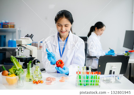 Two Asian scientists in a lab conducting food research using a microscope and lab equipment, showcasing innovation in food science Two Asian scientists in a lab conducting food research using a microscope and lab equipment, showcasing innovation in food science 132801945