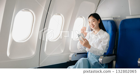 Attractive Asian female passenger of airplane sitting in comfortable seat while working laptop and tablet with mock up area using wireless connection. Attractive Asian female passenger of airplane sitting in comfortable seat while working laptop and tablet with mock up area using wireless connection. 132802065