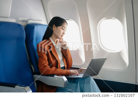 Young Asian executive excels in first class, multitasking with digital tablet, laptop and smartphone. Travel in style, work Young Asian executive excels in first class, multitasking with digital tablet, laptop and smartphone. Travel in style, work 132802107