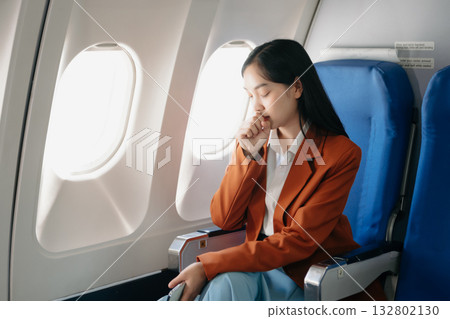 Photo of a frustrated woman sitting on an airplane with her head in her hands. woman sitting in a seat in airplane Photo of a frustrated woman sitting on an airplane with her head in her hands. woman sitting in a seat in airplane 132802130