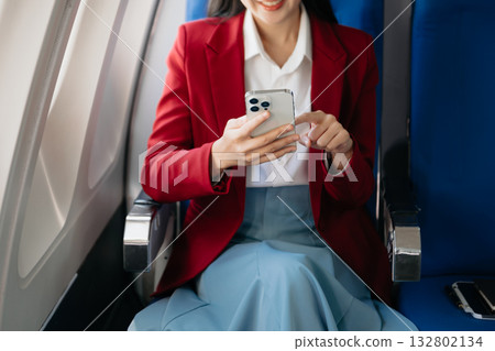 Attractive Asian female passenger of airplane sitting in comfortable seat while working laptop and tablet with mock up area using wireless connection. 132802134