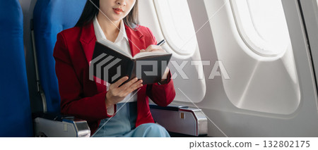Young Asian executive excels in first class, multitasking with digital tablet, laptop and smartphone. Travel in style, work 132802175