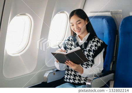 Young Asian executive excels in first class, multitasking with digital tablet, laptop and smartphone. Travel in style, work Young Asian executive excels in first class, multitasking with digital tablet, laptop and smartphone. Travel in style, work 132802214