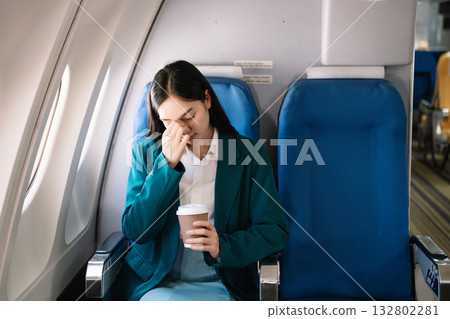 Photo of a frustrated woman sitting on an airplane with her head in her hands. Asian woman sitting in a seat 132802281