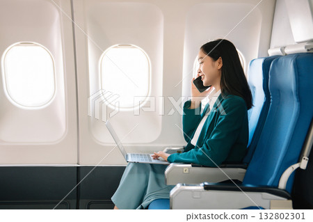 Attractive Asian female passenger of airplane sitting in comfortable seat while working laptop and tablet with mock up area using wireless connection. Attractive Asian female passenger of airplane sitting in comfortable seat while working laptop and tablet with mock up area using wireless connection. 132802301