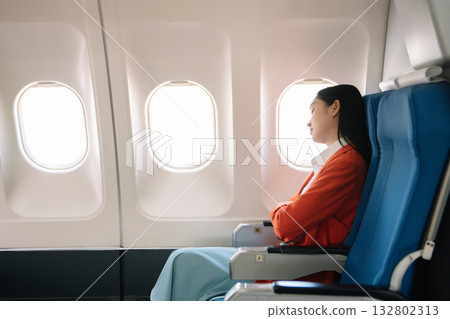 Photo of a frustrated woman sitting on an airplane with her head in her hands. Asian woman sitting in a seat 132802313