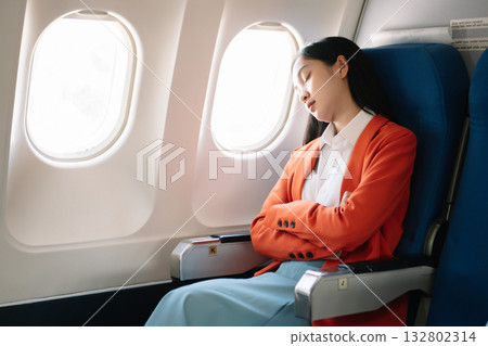Photo of a frustrated woman sitting on an airplane with her head in her hands. Asian woman sitting in a seat 132802314
