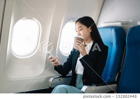 Attractive Asian female passenger of airplane sitting in comfortable seat while working laptop and tablet with mock up area using wireless connection. Attractive Asian female passenger of airplane sitting in comfortable seat while working laptop and tablet with mock up area using wireless connection. 132802448