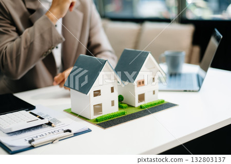 balancing the property sector The real estate agent is explaining the house style to see the house design and the purchase agreement. 132803137