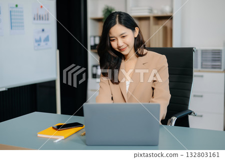 Young beautiful woman typing on tablet and laptop while sitting at the working white table Young beautiful woman typing on tablet and laptop while sitting at the working white table 132803161