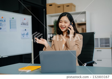 Young beautiful woman typing on tablet and laptop while sitting at the working white table 132803167