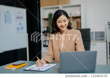Young beautiful woman typing on tablet and laptop while sitting at the working white table Young beautiful woman typing on tablet and laptop while sitting at the working white table 132803170