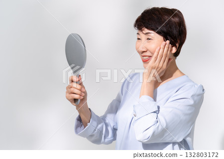 Senior woman looking in the mirror smiling Senior woman looking in the mirror smiling 132803172