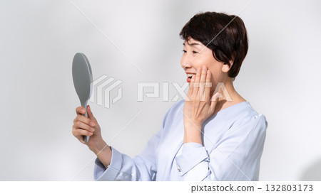 Senior woman looking in the mirror smiling Senior woman looking in the mirror smiling 132803173