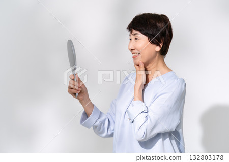 Senior woman looking in the mirror smiling 132803178
