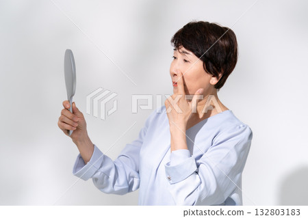 Senior woman looking in the mirror worries Senior woman looking in the mirror worries 132803183
