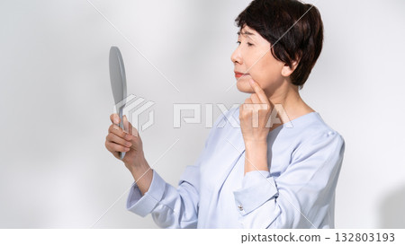 Senior woman looking in the mirror worries Senior woman looking in the mirror worries 132803193