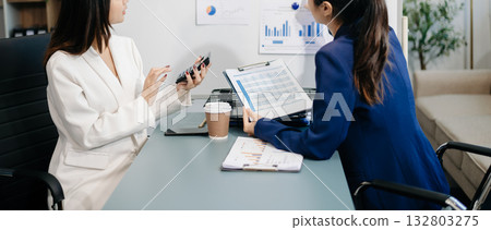 Businesswomen work and discuss their business plans. A Human employee explains and shows her colleague the results paper Businesswomen work and discuss their business plans. A Human employee explains and shows her colleague the results paper 132803275
