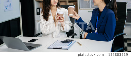 Female discussing new project with Female colleague. Young women talking with young Asian man in office. 132803319