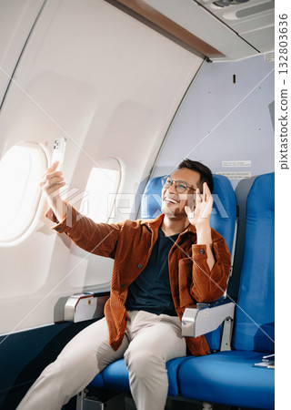 Asian male passenger of airplane sitting in comfortable seat while working laptop and tablet with mock up area using wireless connection. Travel in style, Asian male passenger of airplane sitting in comfortable seat while working laptop and tablet with mock up area using wireless connection. Travel in style, 132803636