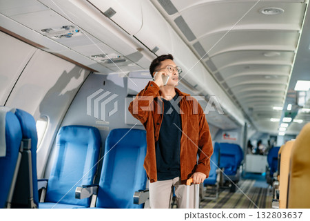 Asian male passenger of airplane sitting in comfortable seat while working laptop and tablet with mock up area using wireless connection. Travel in style, Asian male passenger of airplane sitting in comfortable seat while working laptop and tablet with mock up area using wireless connection. Travel in style, 132803637
