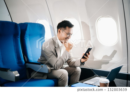 Young Asian executive excels in first class, multitasking with digital tablet, laptop and smartphone. Travel in style, Young Asian executive excels in first class, multitasking with digital tablet, laptop and smartphone. Travel in style, 132803639