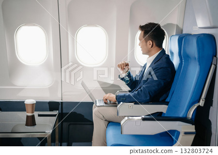 Young Asian executive excels in first class, multitasking with digital tablet, laptop and smartphone. Travel in style, Young Asian executive excels in first class, multitasking with digital tablet, laptop and smartphone. Travel in style, 132803724