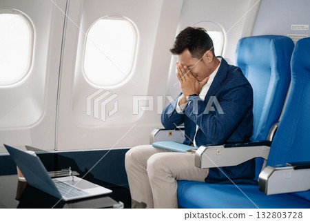 Photo of a frustrated man sitting on an airplane with her head in her hands. Asian Businessman sitting 132803728