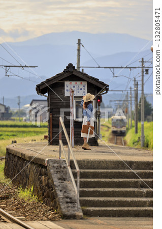 A woman waiting for a train on the platform of a rural station 132805471
