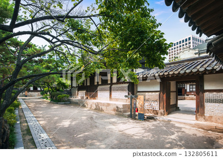 A tranquil garden path and entry gate surrounded by leafy trees and traditional stone walls at Unhyeongung Palace, blending natural serenity with Joseon-era architecture 132805611