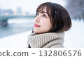 A woman in a turtleneck knit looking up at the snowy sky 132806576