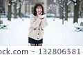 A smiling woman playing in the snow in a knitted sweater and skirt in a snowy park 132806581