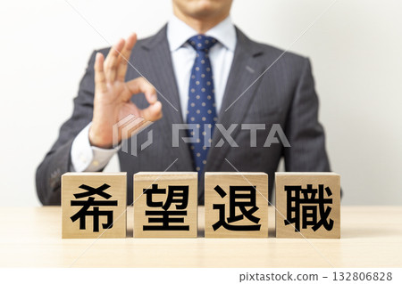 一位商人擺出「OK」的手勢,旁邊立著一塊寫著「自願退休」的牌子。 一位商人擺出「OK」的手勢,旁邊立著一塊寫著「自願退休」的牌子。 132806828