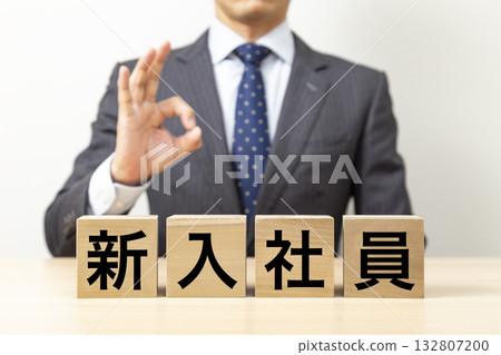一位商人擺出「OK」的姿勢，旁邊立著一塊寫著「新進員工」的牌子。 132807200