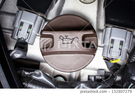Close-up of an engine oil cap with oil symbol, motor oil change, engine lubrication Close-up of an engine oil cap with oil symbol, motor oil change, engine lubrication 132807279