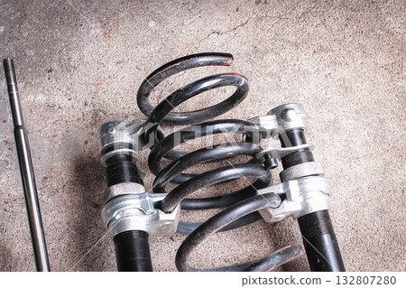 Car shock spring being removed with spring removal tool for replacement in auto repair shop 132807280
