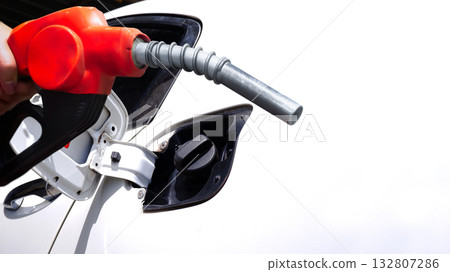 Close-up of a red fuel pump nozzle inserted into a car gas tank Close-up of a red fuel pump nozzle inserted into a car gas tank 132807286