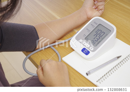 A person's hand measuring blood pressure with a home blood pressure monitor A person's hand measuring blood pressure with a home blood pressure monitor 132808631