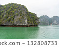 A captivating view of the emerald waters surrounding limestone karsts in Ha Long Bay, Vietnam, under an overcast sky. 132808733