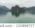 A serene view of the iconic Ha Long Bay, showcasing floating villages, limestone karsts, and calm waters under a cloudy sky. 132808737