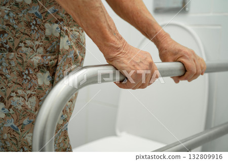 Asian elderly woman patient use toilet support rail in bathroom. Asian elderly woman patient use toilet support rail in bathroom. 132809916