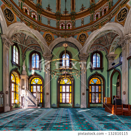 Sunlit interior of Salepcioglu Mosque, showcasing its ornate dome, calligraphy, and vibrant carpet, Izmir, Turkey. Sunlit interior of Salepcioglu Mosque, showcasing its ornate dome, calligraphy, and vibrant carpet, Izmir, Turkey. 132810115