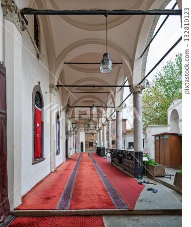 Historic Hisar Mosque covered walkway with red prayer carpet, arches, and lanterns, Izmir, Turkey. Historic Hisar Mosque covered walkway with red prayer carpet, arches, and lanterns, Izmir, Turkey. 132810123