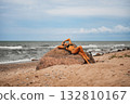 A peaceful and serene beach scene depicts a woman reclining on a rock while enjoying the stunning ocean view 132810167